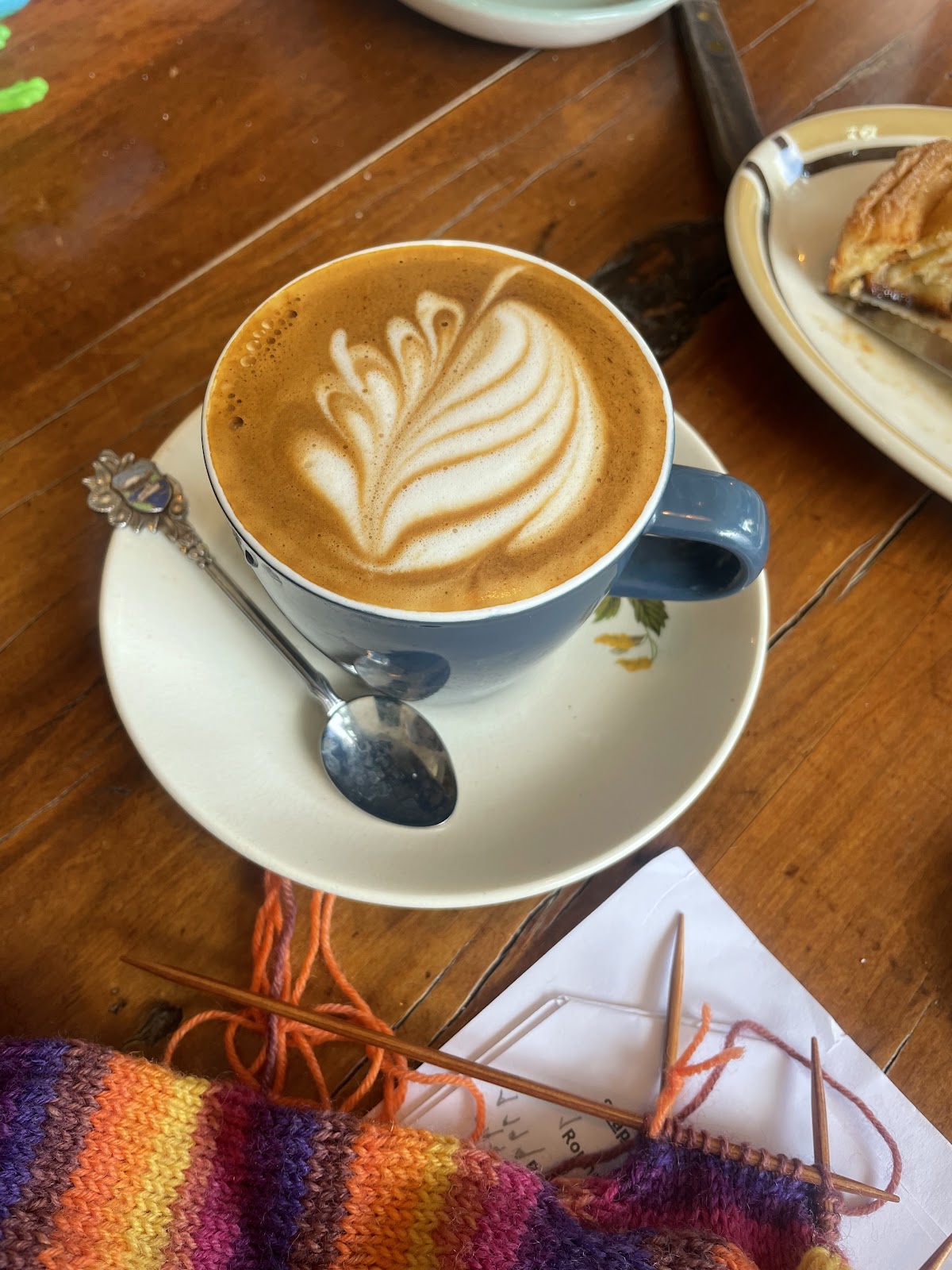 Flat white with latte art beside some knitting
